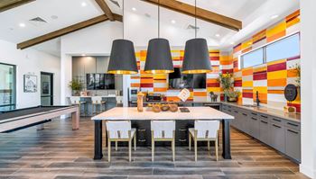 A dining room with a table and chairs in front of a kitchen with a counter